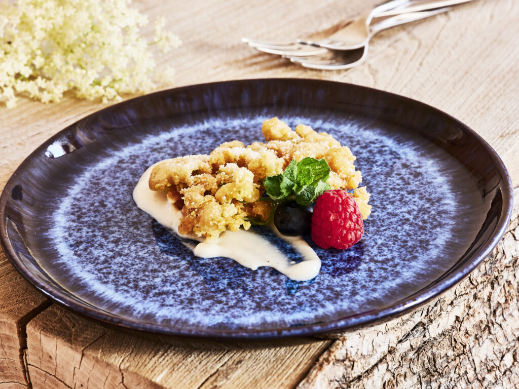 Holunderblüten-Kücherl mit Johgurt-Dip und Beeren, angerichtet auf einem blauen Teller