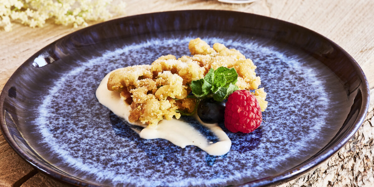 Holunderblüten-Kücherl mit Johgurt-Dip und Beeren, angerichtet auf einem blauen Teller